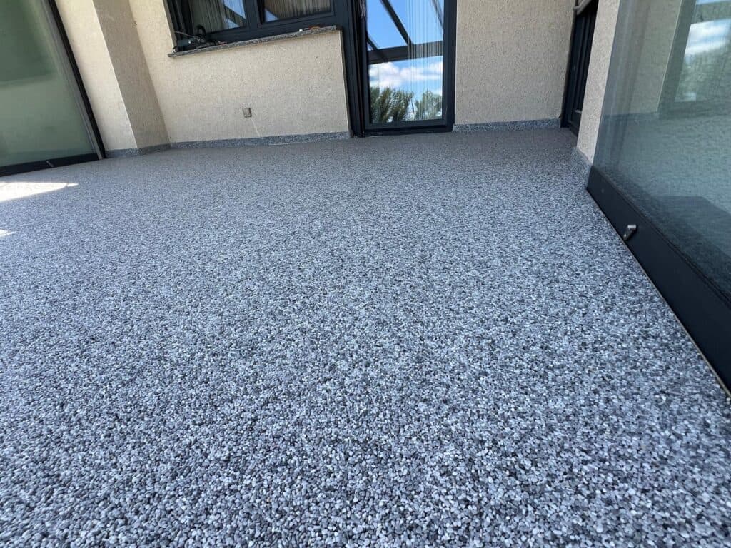 Terrasse mit hellgrauem Steinteppich, fugenlos bis an die Fassade verlegt